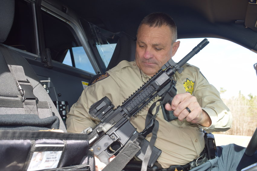 Neshoba County Sheriff Eric Clark locks up an AR-15 patrol rifle in a squad car.
